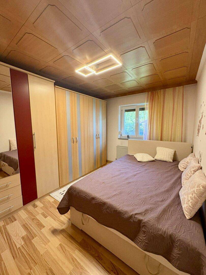 Schlafzimmer mit großem Kleiderschrank, Doppelbett und einer Holzpaneeldecke.