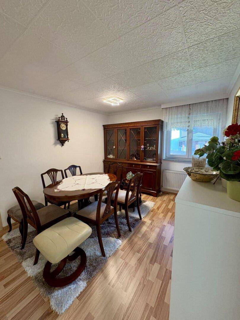 Traditionelles Esszimmer mit klassischem Holztisch, Stühlen und einem Vitrinenschrank.