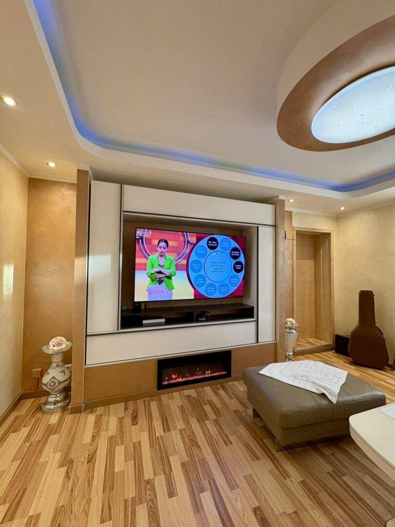 Helles Wohnzimmer mit modernem TV-Möbel, elektrischem Kamin und stimmungsvoller Beleuchtung.