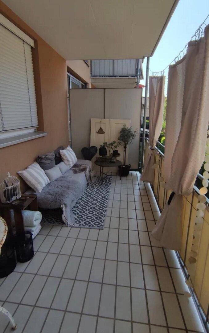 Gemütlicher Balkon mit Fliesenboden, Sitzgelegenheiten und Sichtschutz für Privatsphäre.