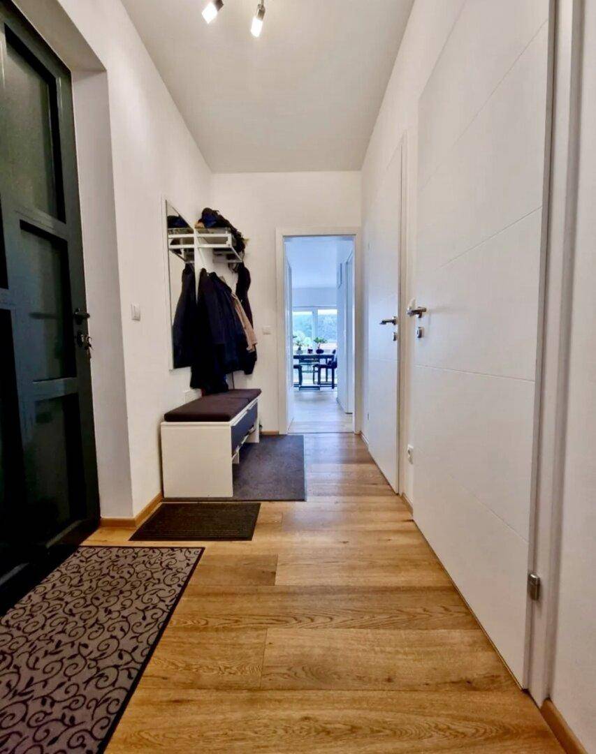 Heller Flur mit Holzfußboden, Garderobe und Zugang zu weiteren Räumen.