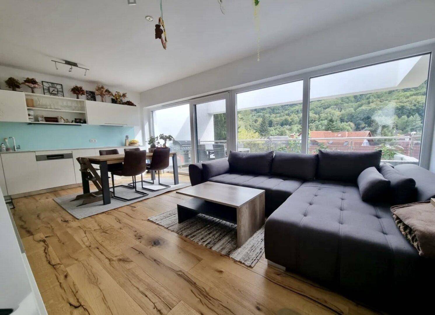 Offener Wohn- und Essbereich mit integrierter Küche, Holzboden und großen Fenstern mit Bergblick.