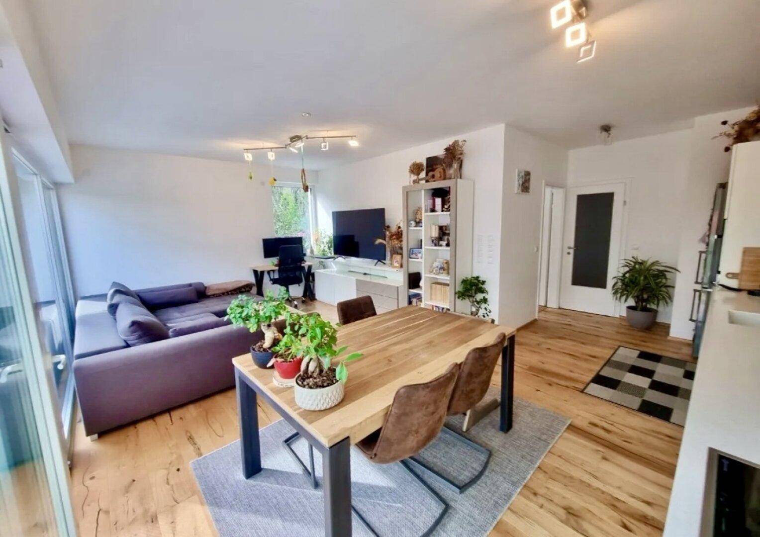 Geräumiger Wohn- und Essbereich mit Holzboden, modernem Esstisch und Arbeitsplatz.