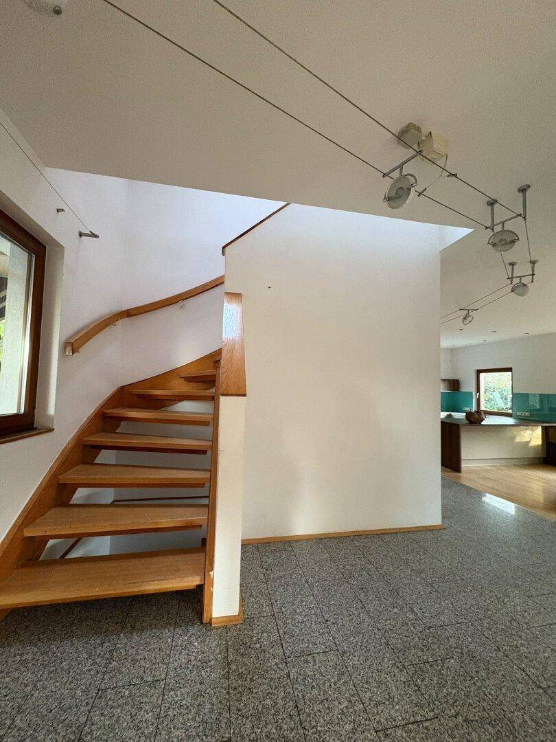 Eingangsbereich mit Granitfliesenboden und einer eleganten Holztreppe, die in die oberen Stockwerke führt.