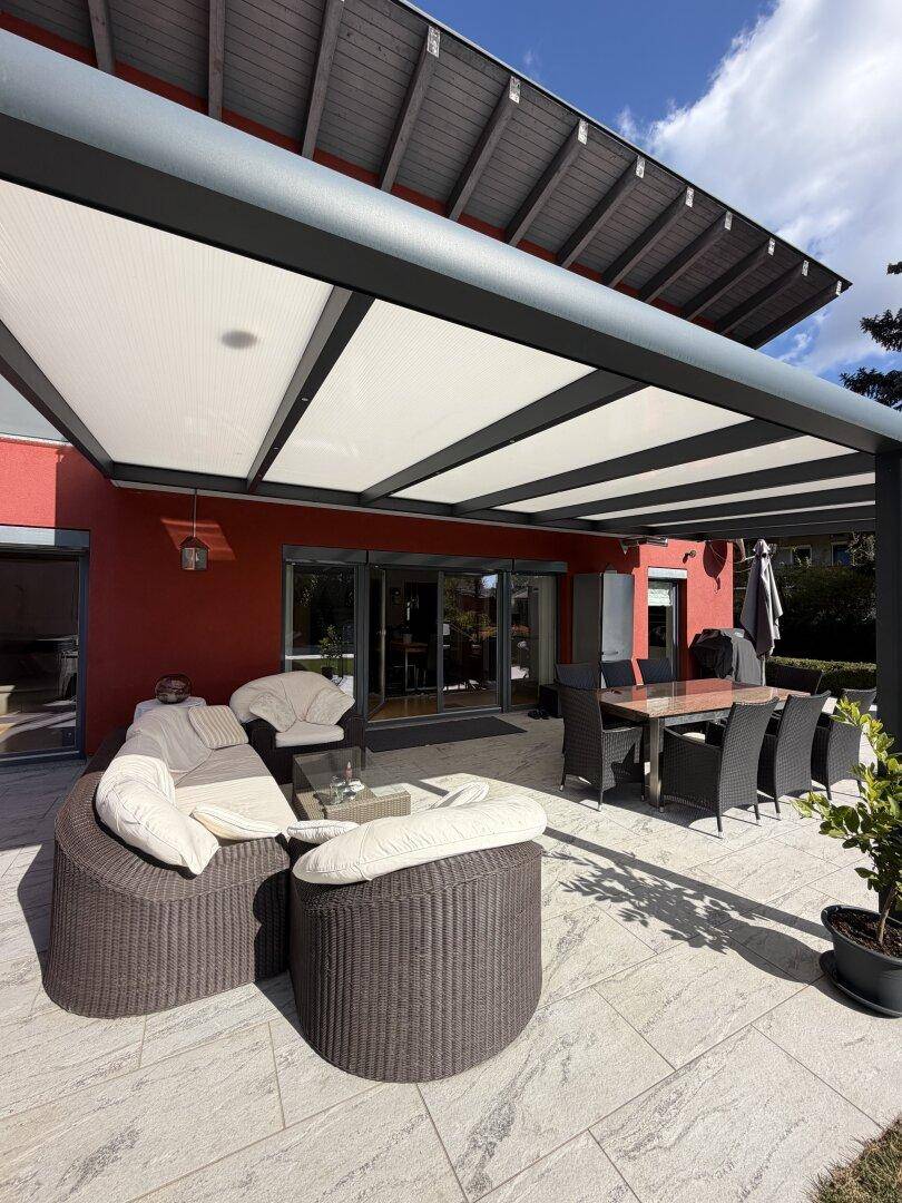 Überdachte Terrasse mit Lounge- und Essbereich, ideal für entspannte Stunden im Freien.