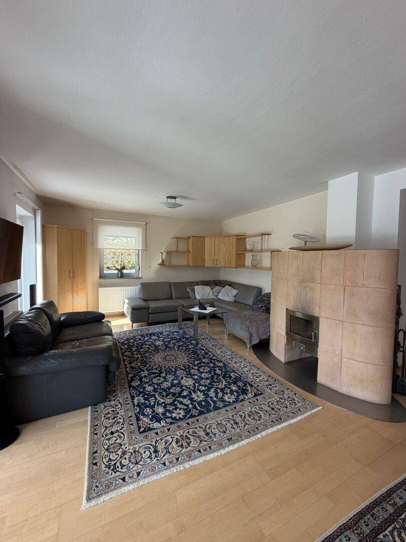 Gemütliches Wohnzimmer mit bequemen Sofas, einem traditionellen Teppich und einem Kachelofen.