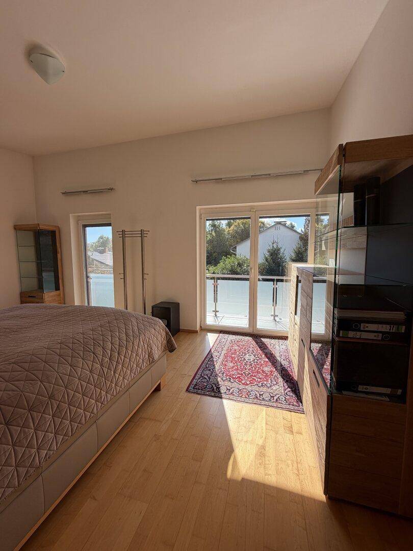 Geräumiges Schlafzimmer mit Doppelbett, Holzmöbeln und Zugang zu einem Balkon.