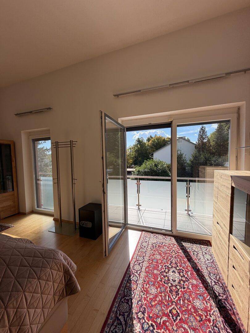 Schlafzimmer mit offener Balkontür, die viel Sonnenlicht und frische Luft hereinlässt.