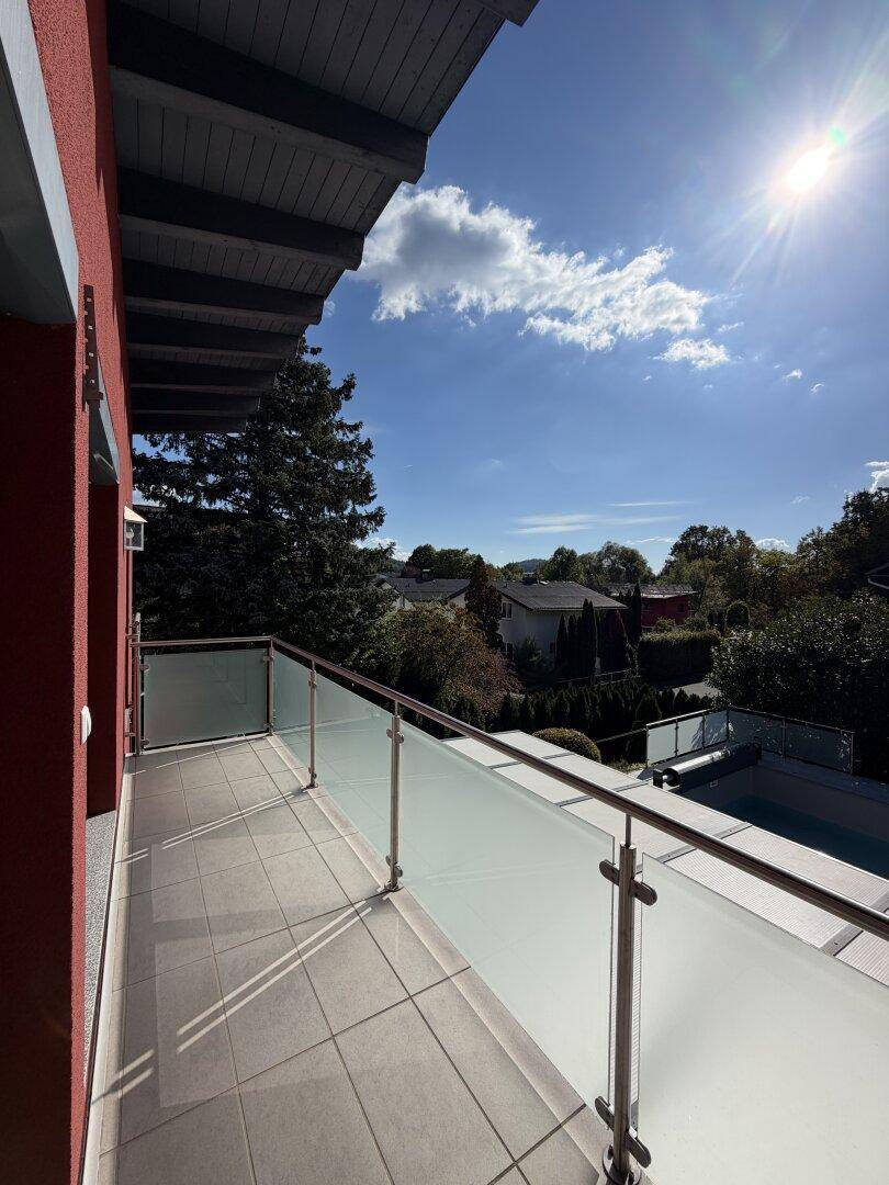Moderner Balkon mit Glasgeländer, bietet einen weiten Blick auf die Umgebung und den Pool.