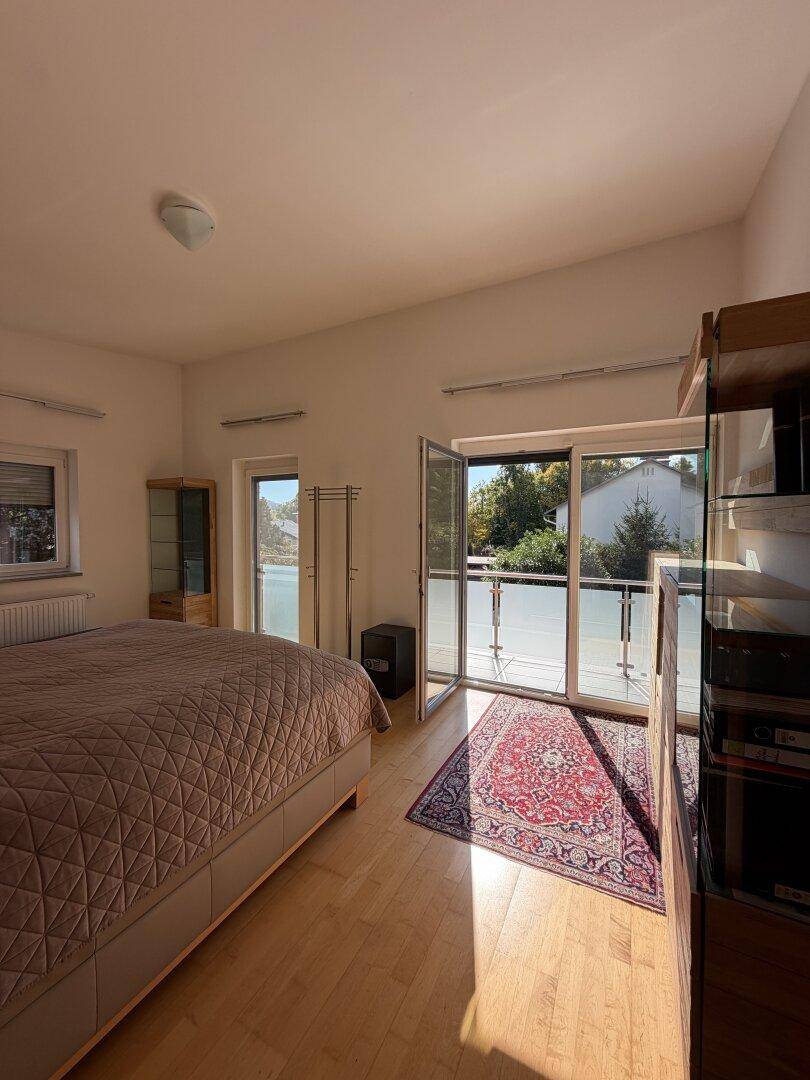 Geräumiges Schlafzimmer mit Doppelbett, Holzmöbeln und Zugang zu einem sonnigen Balkon.