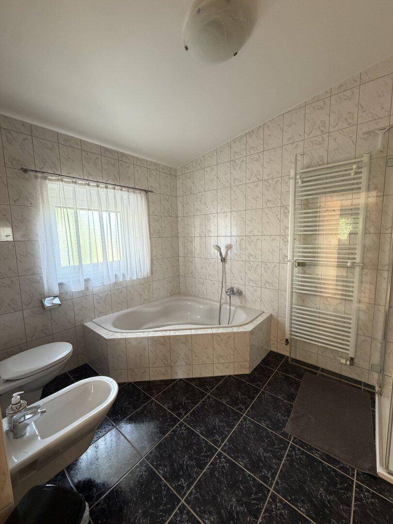 Geräumiges Badezimmer mit Eckbadewanne, Bidet, WC und beheiztem Handtuchhalter.