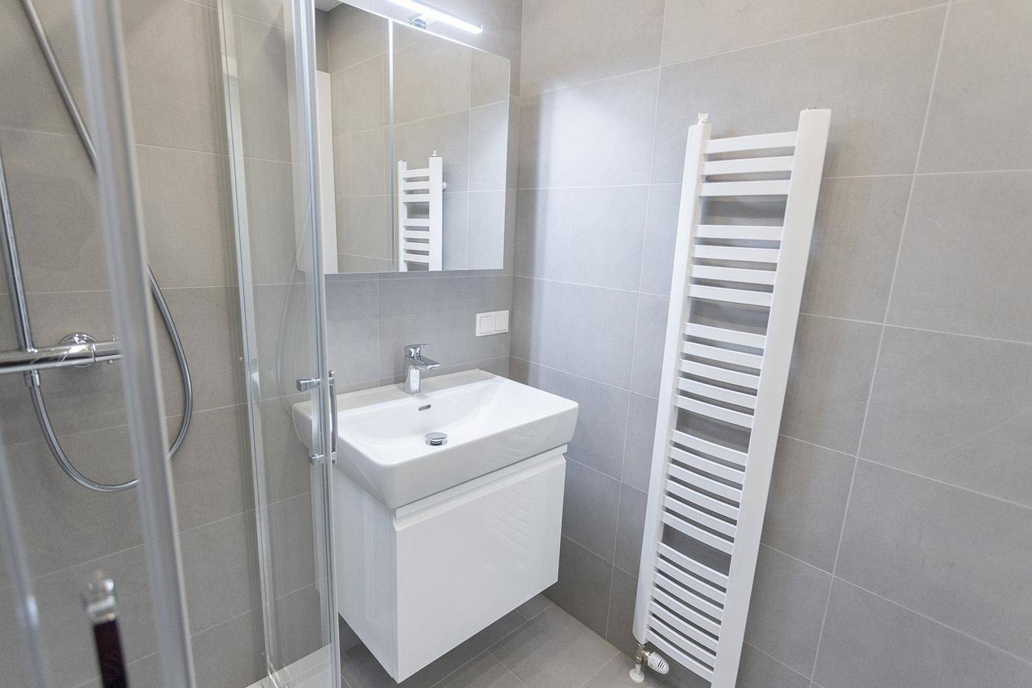 Modernes Badezimmer mit Waschbecken, Spiegel und beheiztem Handtuchhalter an der Wand.