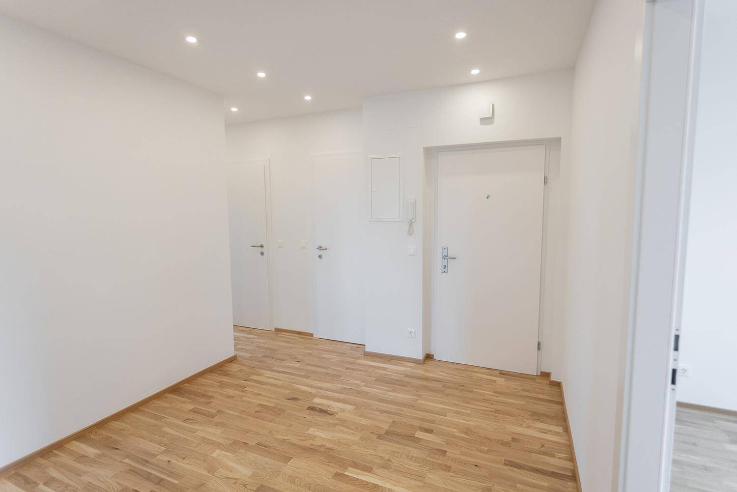 Geräumiger Flur mit hellem Holzparkett und weißen Wänden, bietet Zugang zu weiteren Räumen.