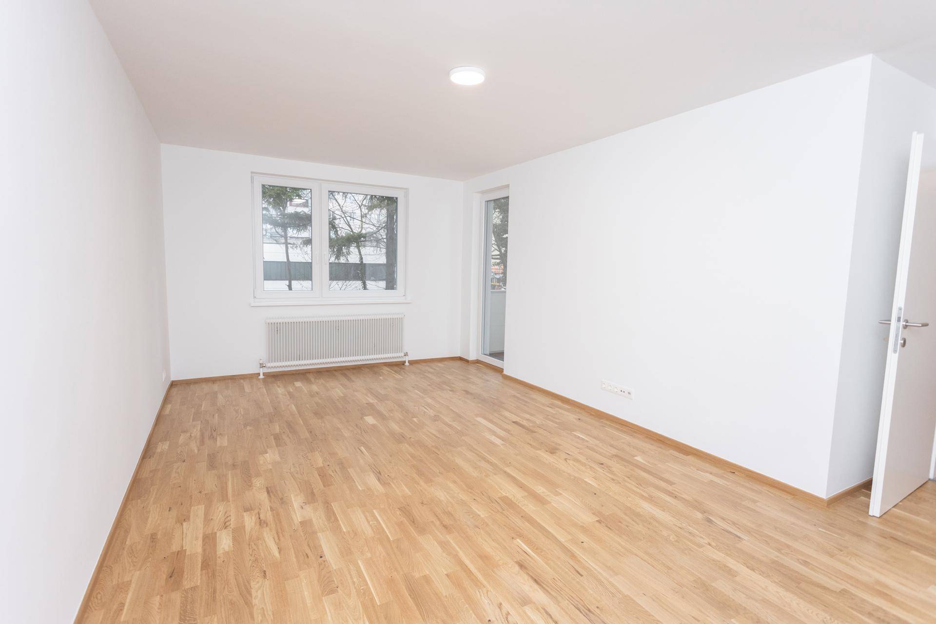 Geräumiger, heller Wohnbereich mit Parkettboden und direktem Zugang zur Loggia.