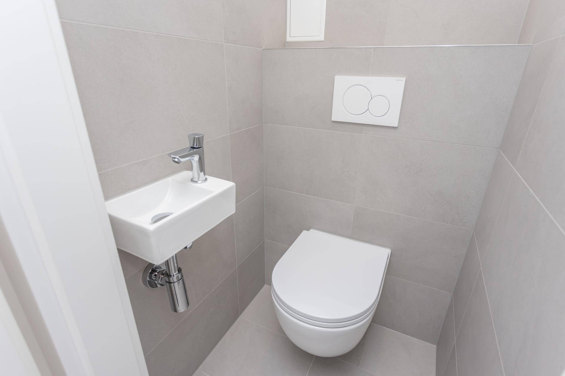 Modernes Gäste-WC mit wandhängendem WC und kleinem Waschbecken.