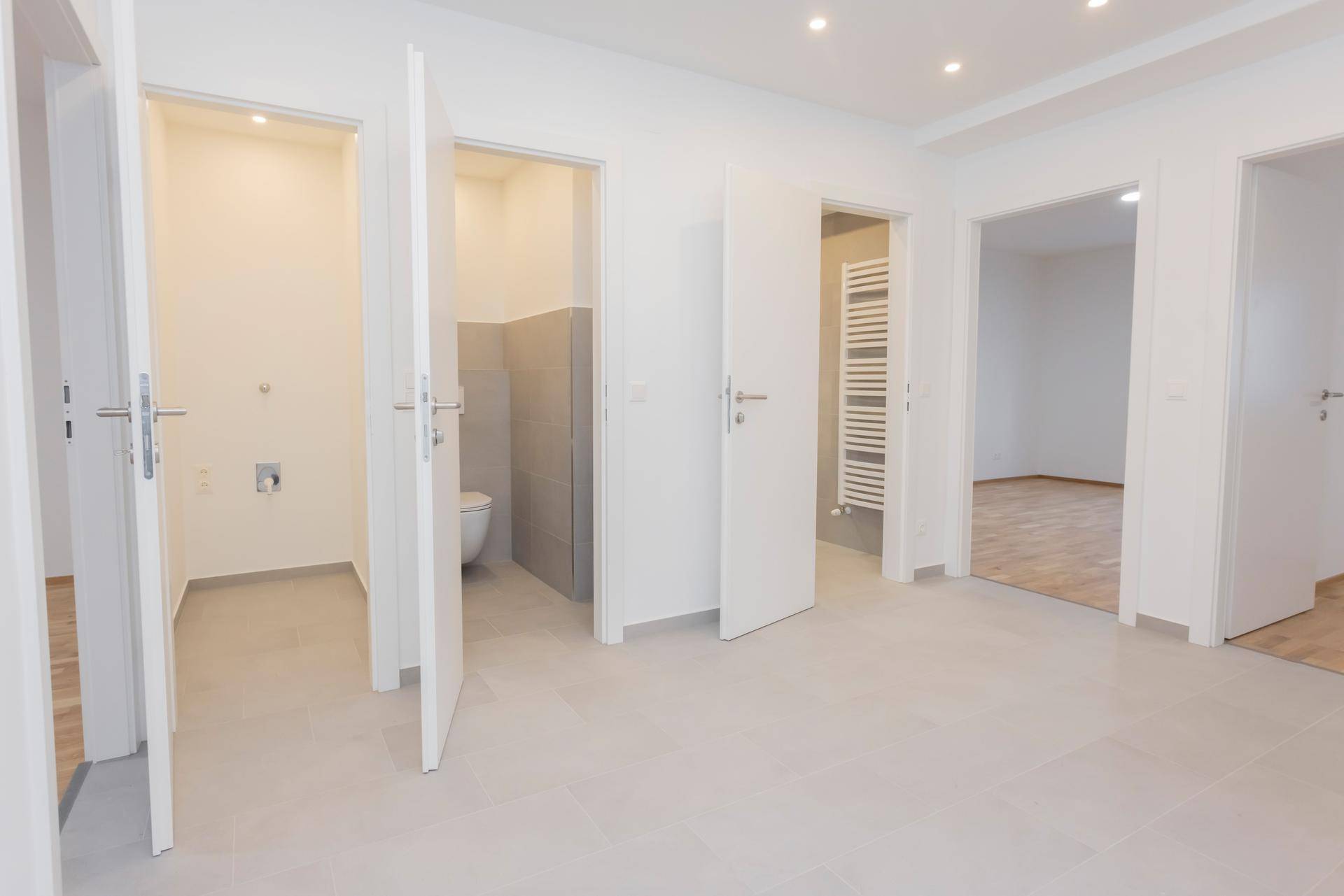 Heller Flur mit Zugang zu einem WC, einem Hauswirtschaftsraum und weiteren Zimmern.