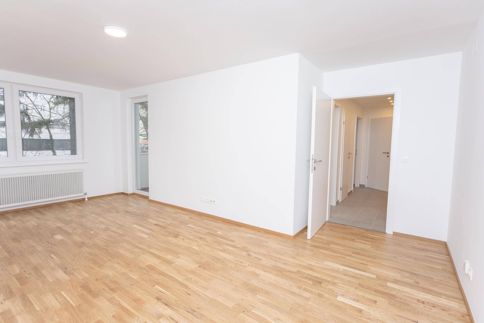 Heller Wohnbereich mit Parkettboden und Zugang zu einer Loggia.