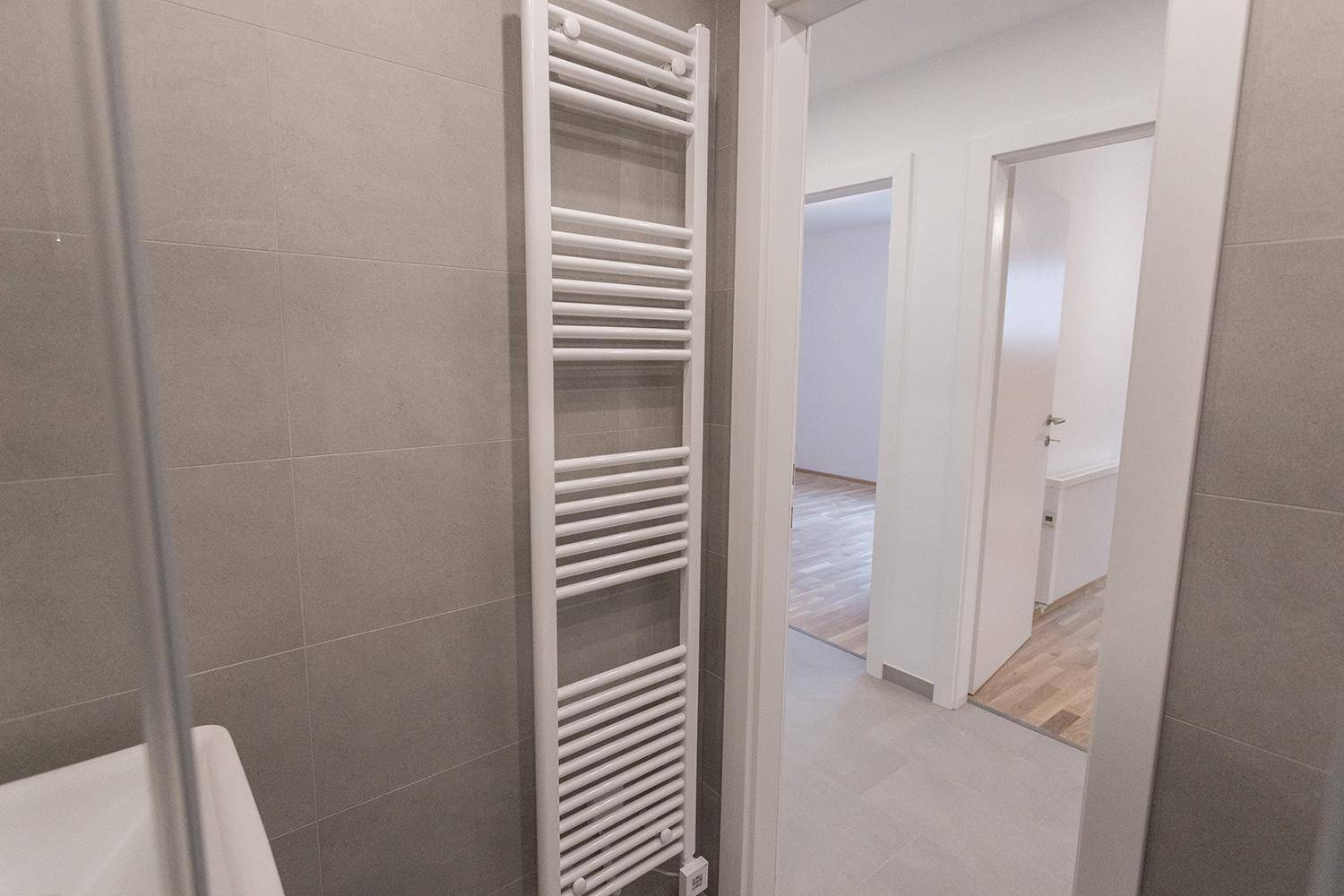Badezimmer mit beheiztem Handtuchhalter und Blick in den angrenzenden Flur.