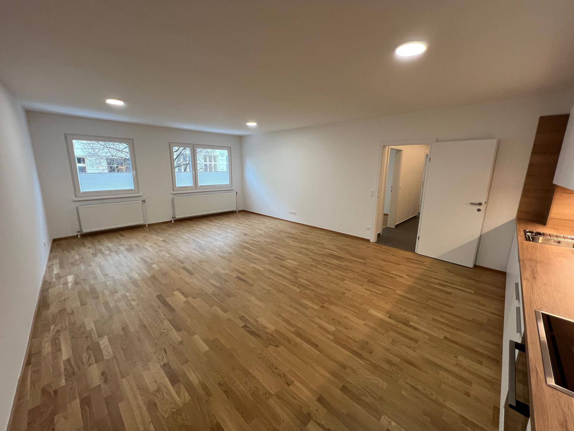 Offener Wohn- und Essbereich mit Holzboden und Blick auf die moderne Küche.