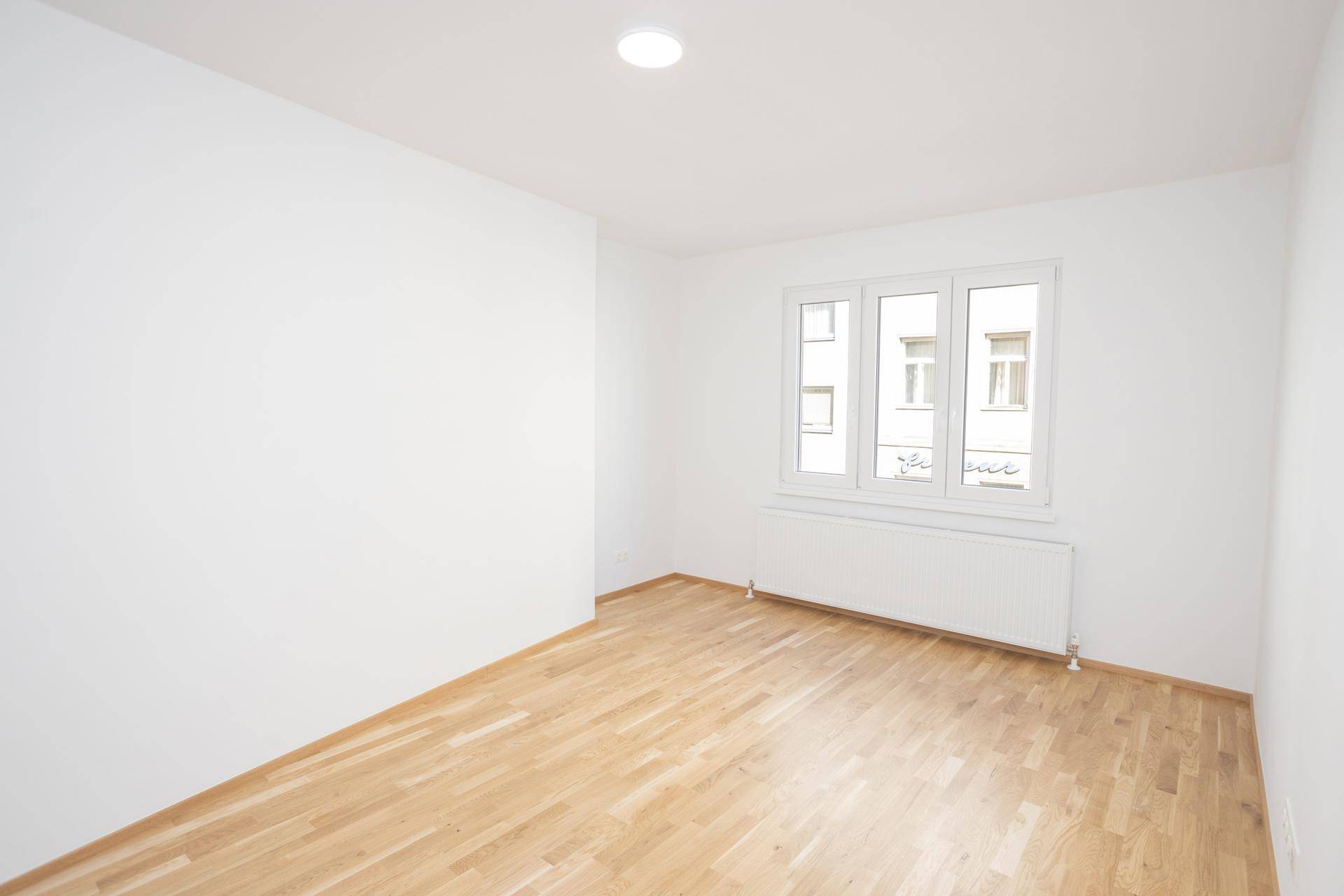 Leeres Zimmer mit Parkettboden und weißen Wänden, bereit für individuelle Gestaltung und Einrichtung.