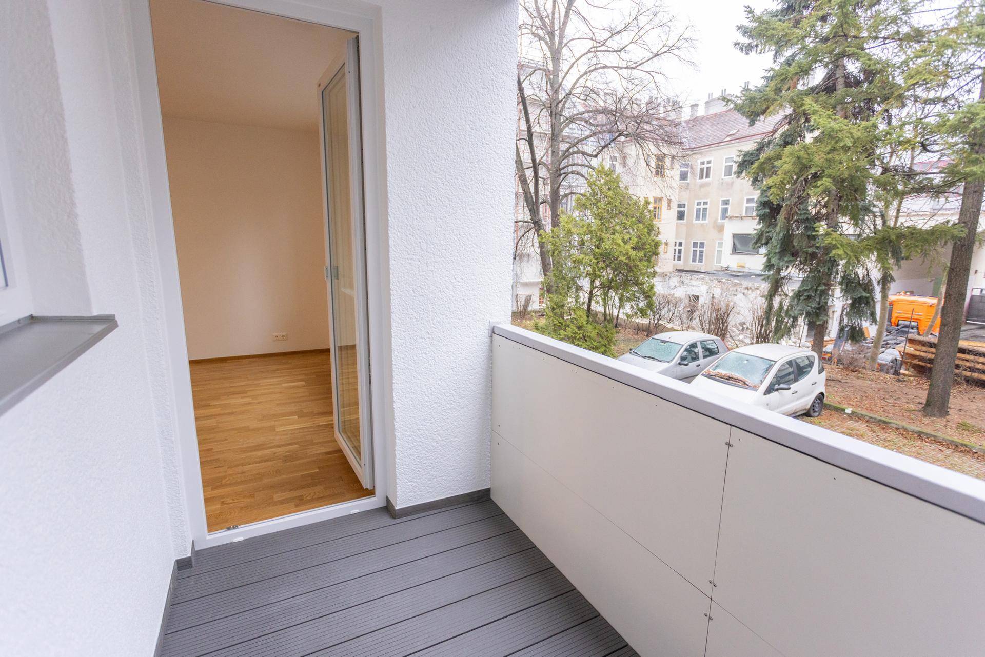 Balkon mit grauem Bodenbelag und offenem Zugang zu einem hellen Innenraum.
