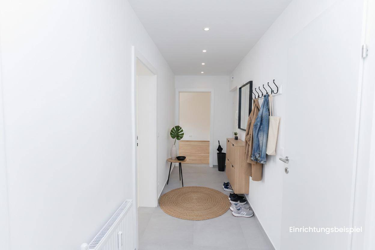 Moderner Flur mit grauen Fliesen, runder Jute-Teppich und Garderobe als Einrichtungsbeispiel.