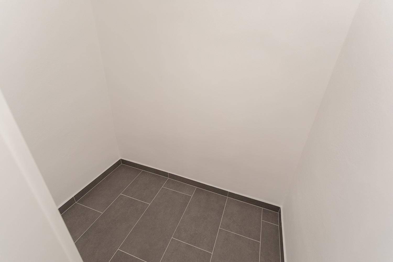 Praktischer Abstellraum mit grauen Fliesen, ideal für zusätzlichen Stauraum.