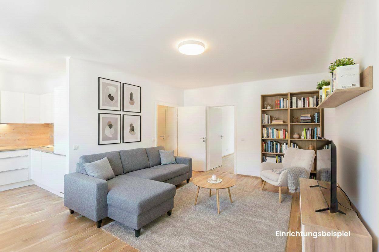 Gemütlicher Wohnbereich mit Sofa, Bücherregal und offener Küche, hell und modern.