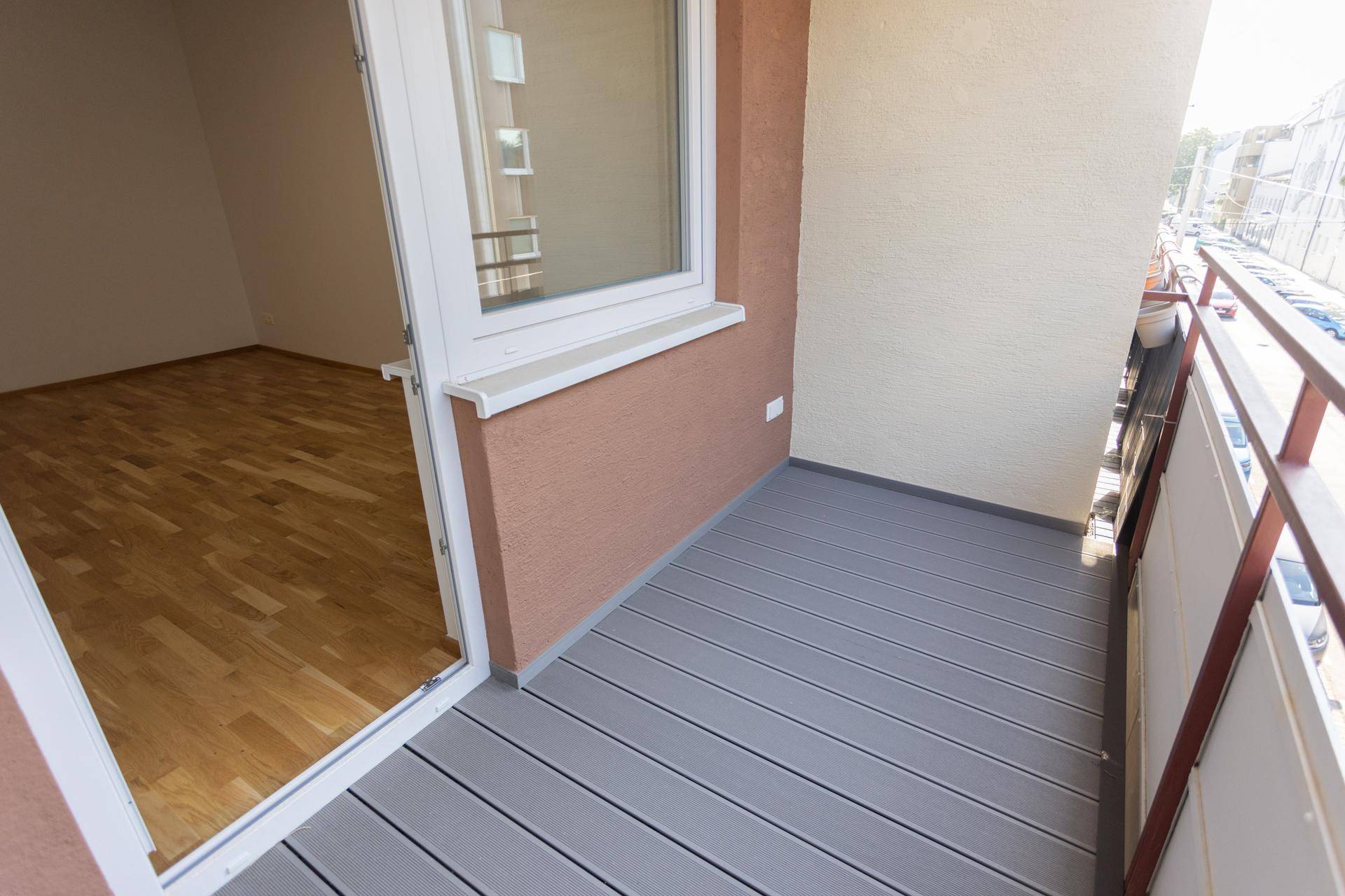 Leerer Balkon mit modernem grauen Bodenbelag und Blick auf die Umgebung.