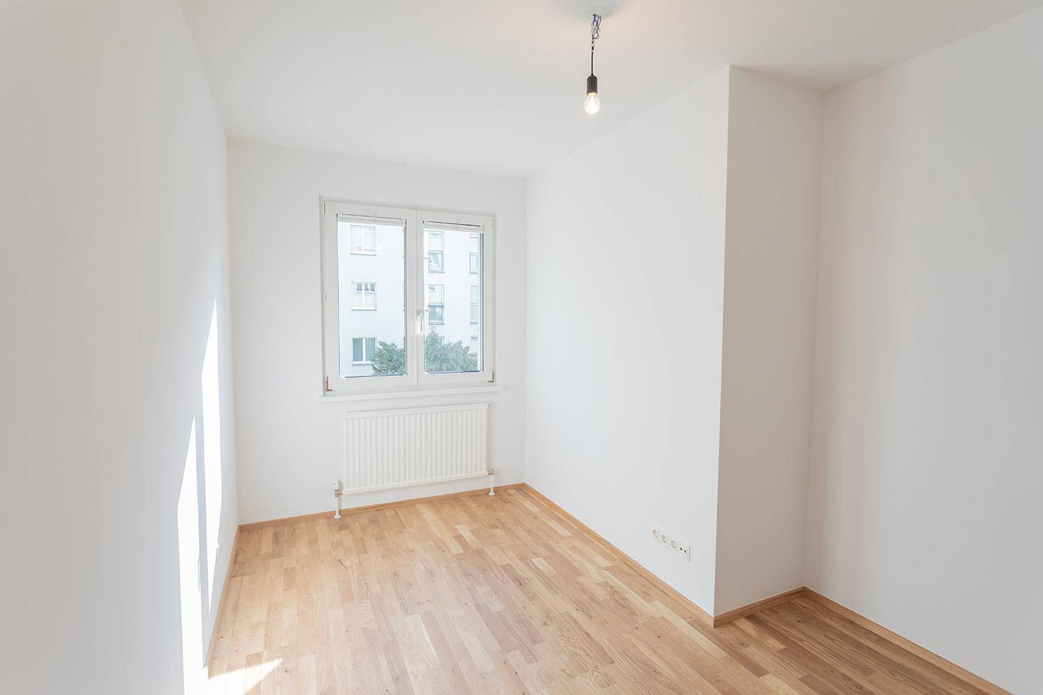 Heller Raum mit Parkettboden und Fenster, das viel Tageslicht hereinlässt.