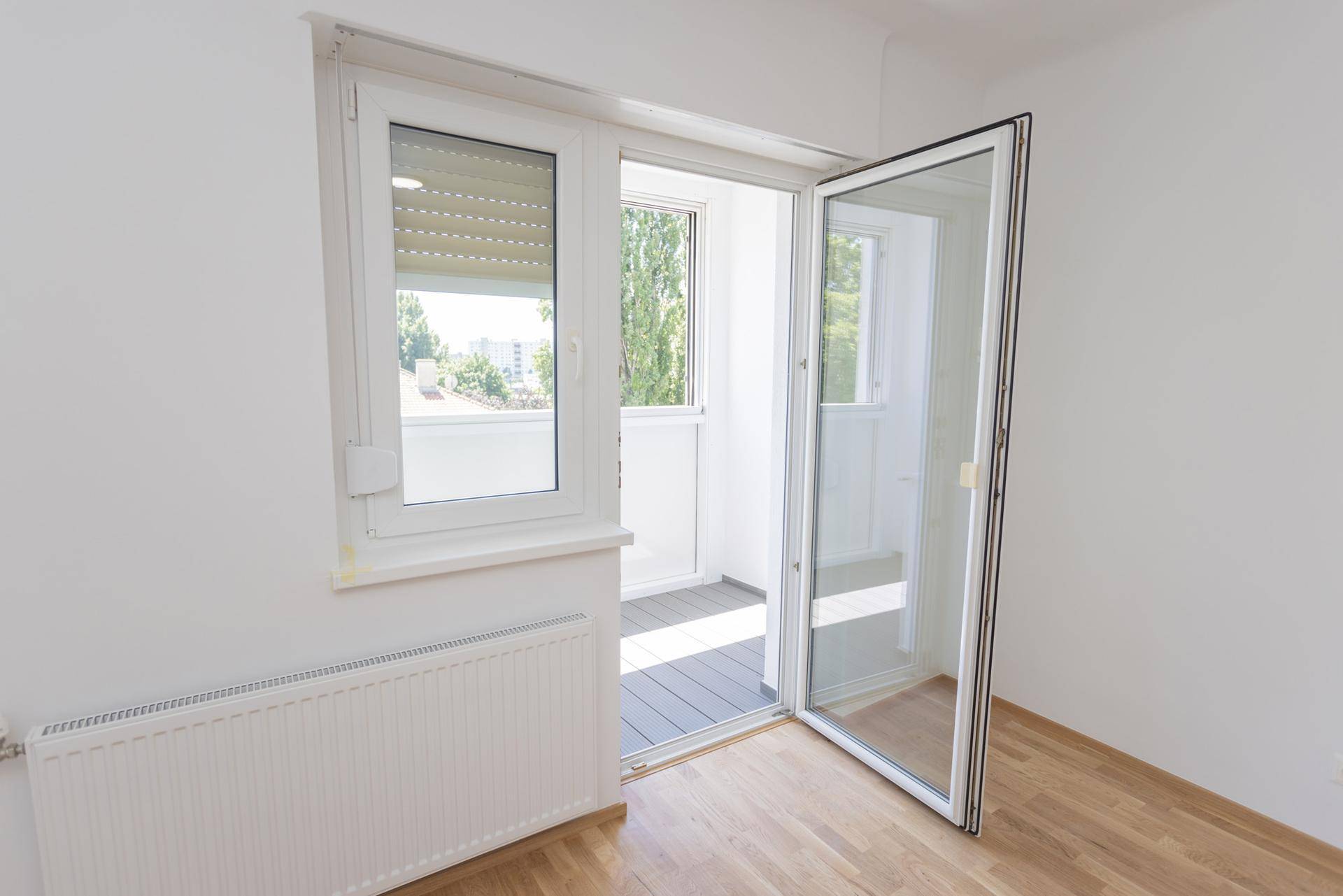 Zugang zu einer hellen Loggia mit großen Fenstern und Blick ins Freie.