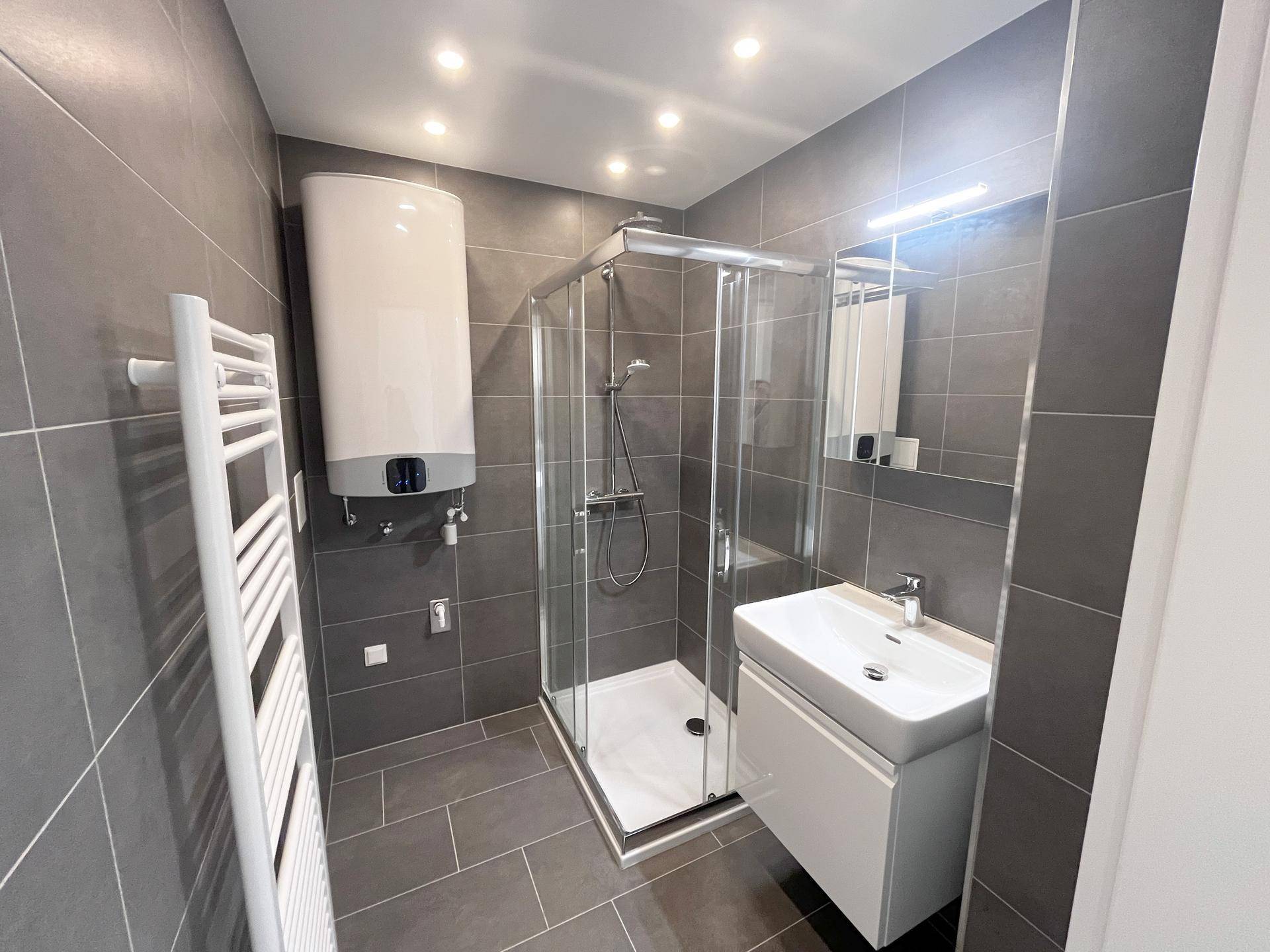 Modernes Badezimmer mit Duschkabine, Waschbecken und beheiztem Handtuchhalter.