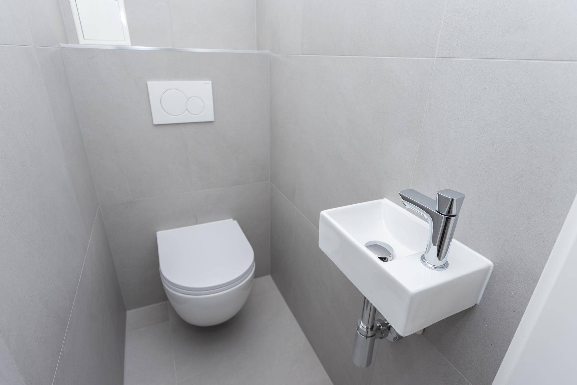 Nahaufnahme eines modernen Gäste-WCs mit wandhängender Toilette und kleinem Waschbecken.