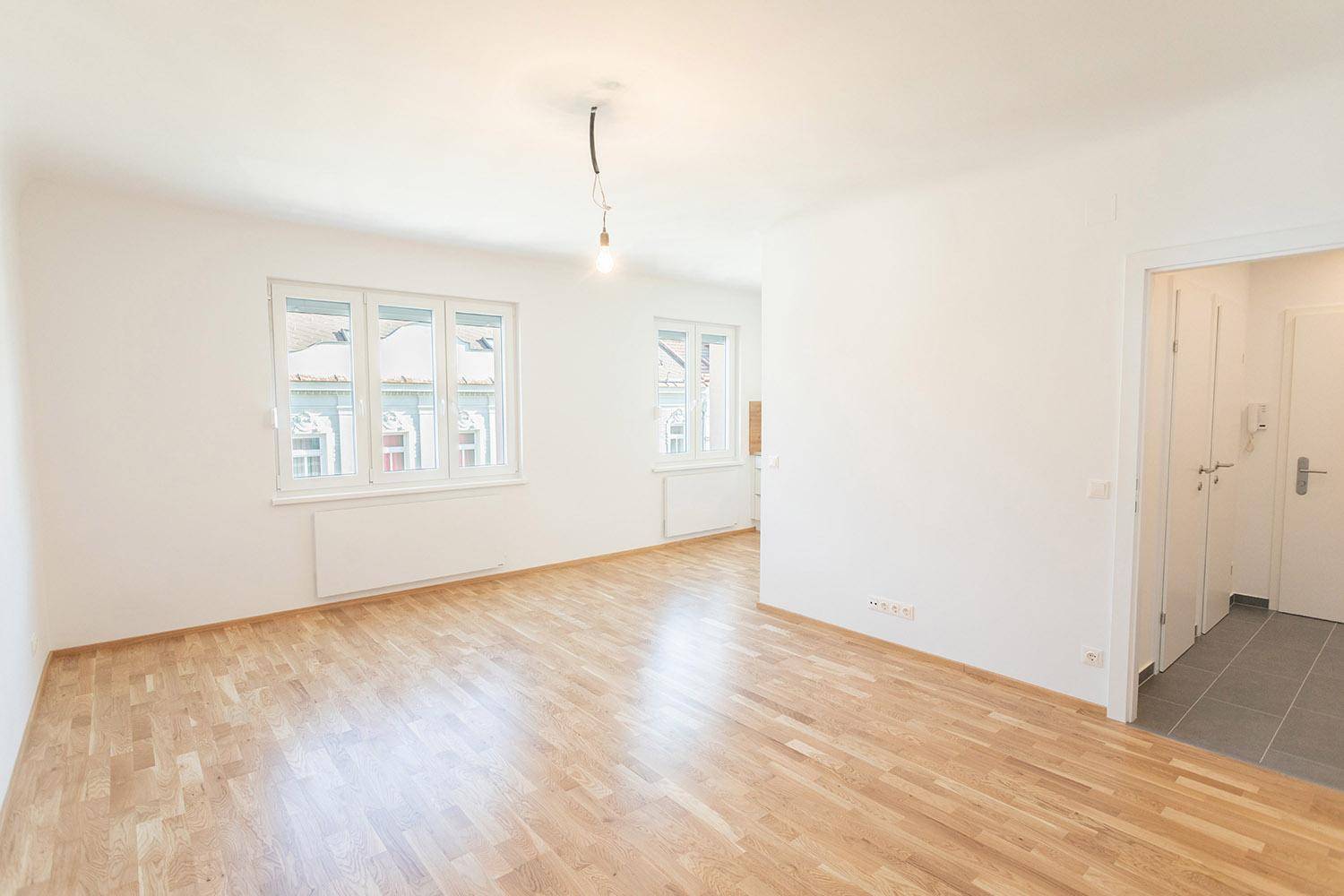 Geräumiger, heller Raum mit Parkettboden und zwei Fenstern, bereit zur Einrichtung.
