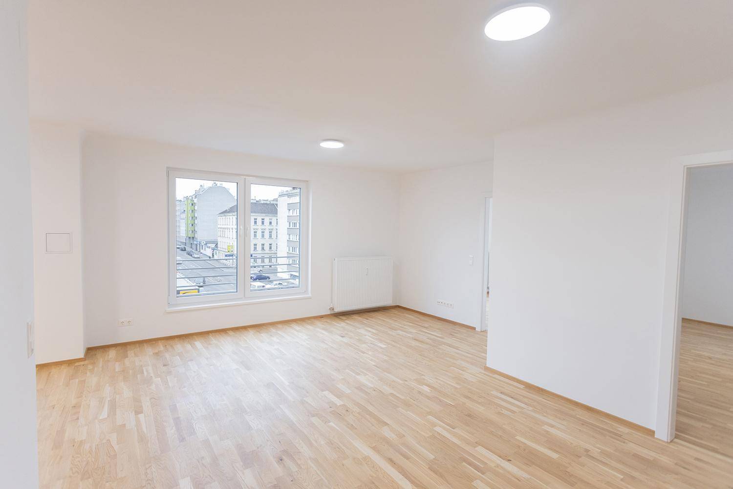 Großer, heller Raum mit Holzboden und weitem Blick auf die Stadtstraße.