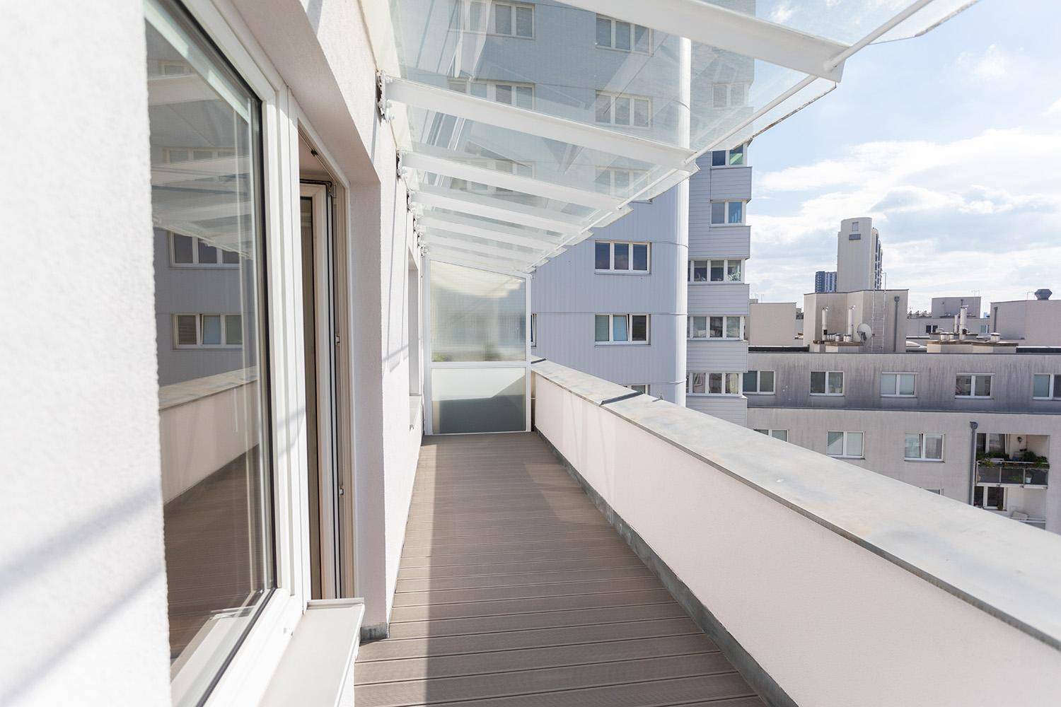 Lange Loggia mit Holzboden und Glasdach, ideal für entspannte Stunden im Freien.