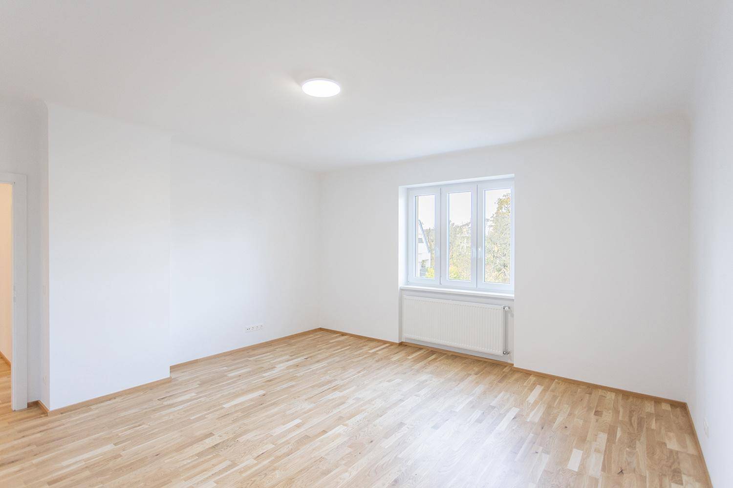 Helles Zimmer mit Holzparkett und Fenster, ideal als Schlaf- oder Arbeitszimmer.