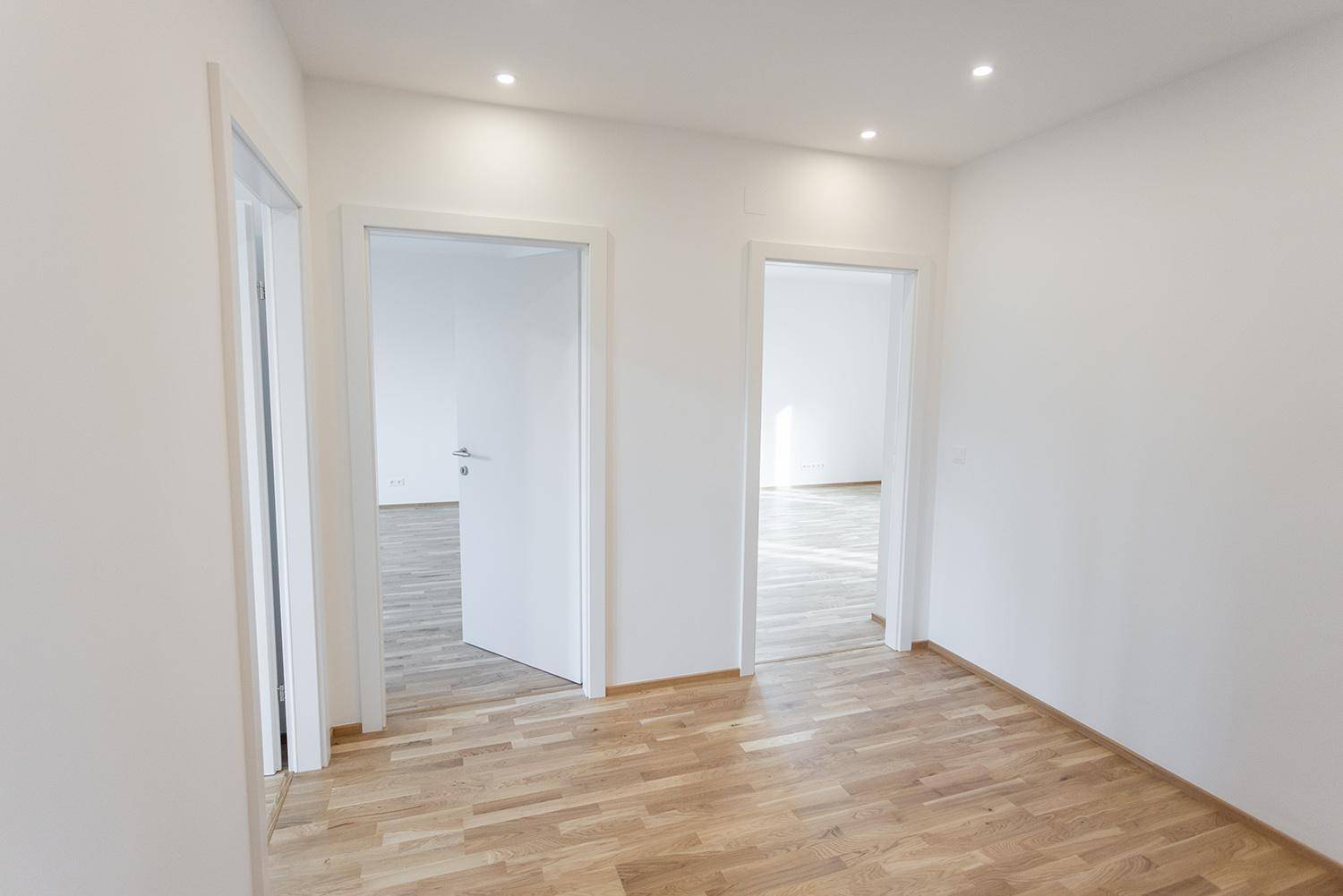 Heller Flur mit Holzparkett und offenen Türen, die den Blick in angrenzende Zimmer freigeben.