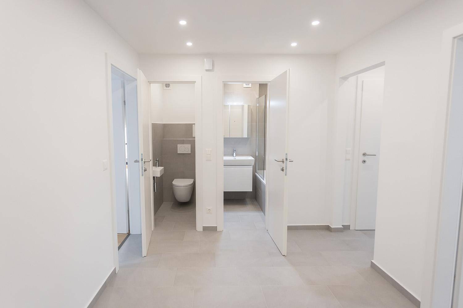 Heller Flur mit Zugang zu einem modernen Badezimmer und einer separaten Gästetoilette.