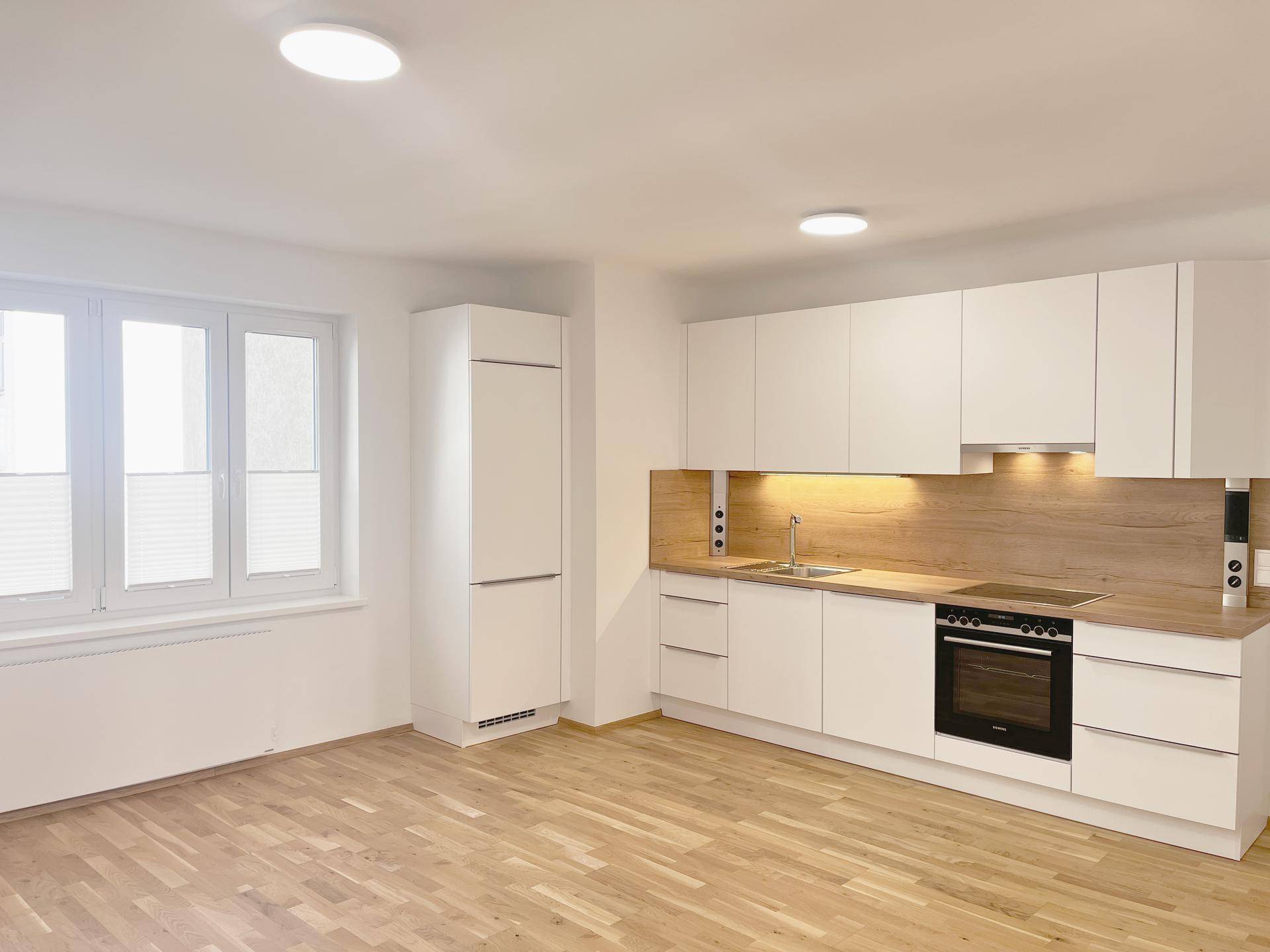 Neue, moderne Einbauküche mit weißen Schränken und Holzarbeitsplatte.