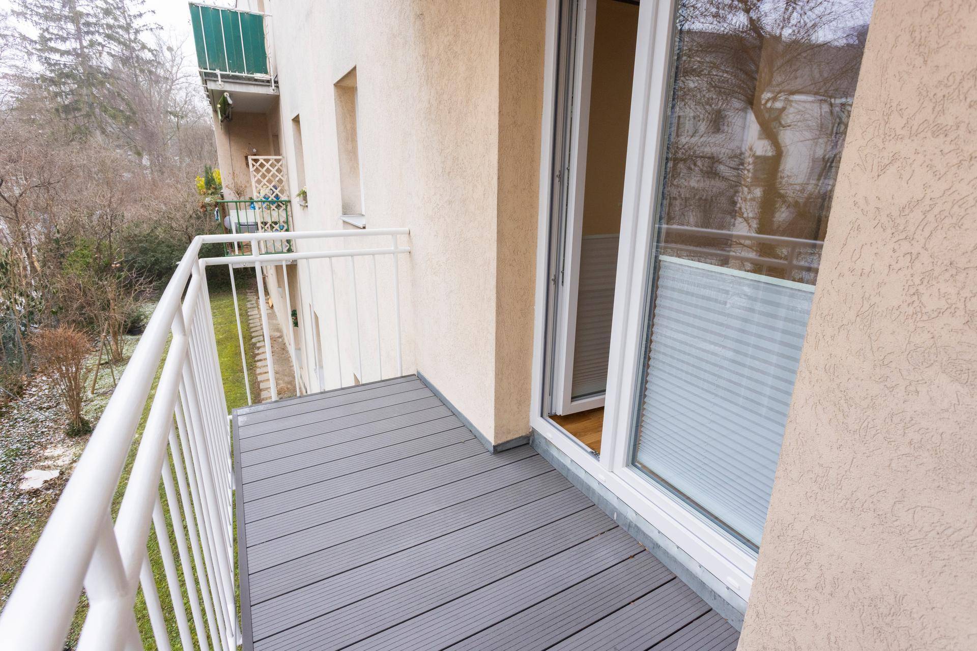 Geräumiger Balkon mit grauen Dielen und Blick auf die umliegende Wohngegend.