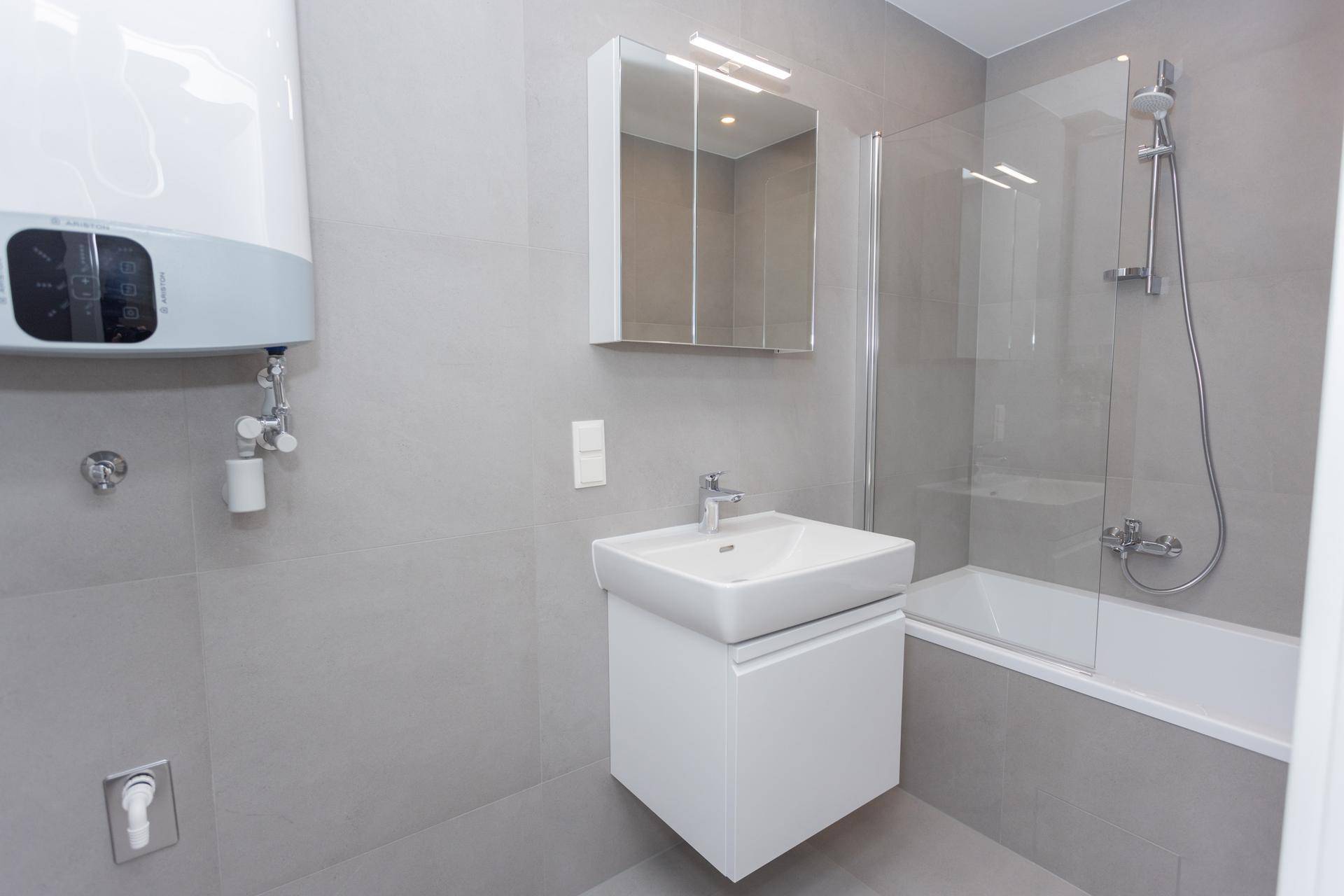 Modernes Badezimmer mit Badewanne, Duschabtrennung, Waschbecken und Spiegelschrank.