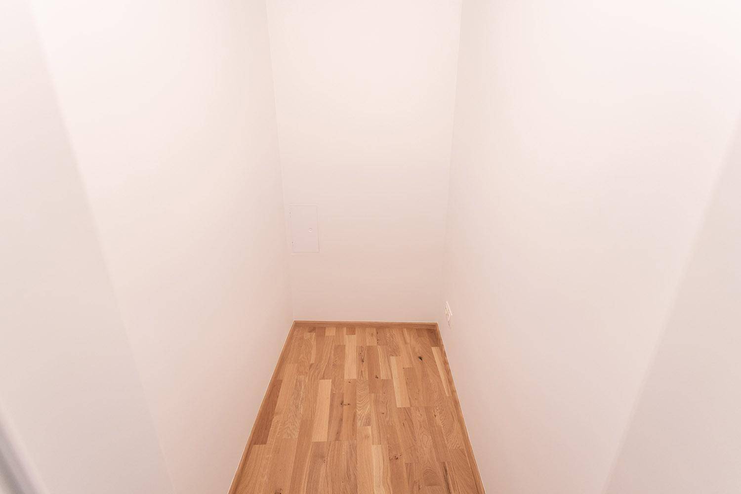 Kleiner, leerer Abstellraum mit hellem Holzboden, ideal für zusätzlichen Stauraum.