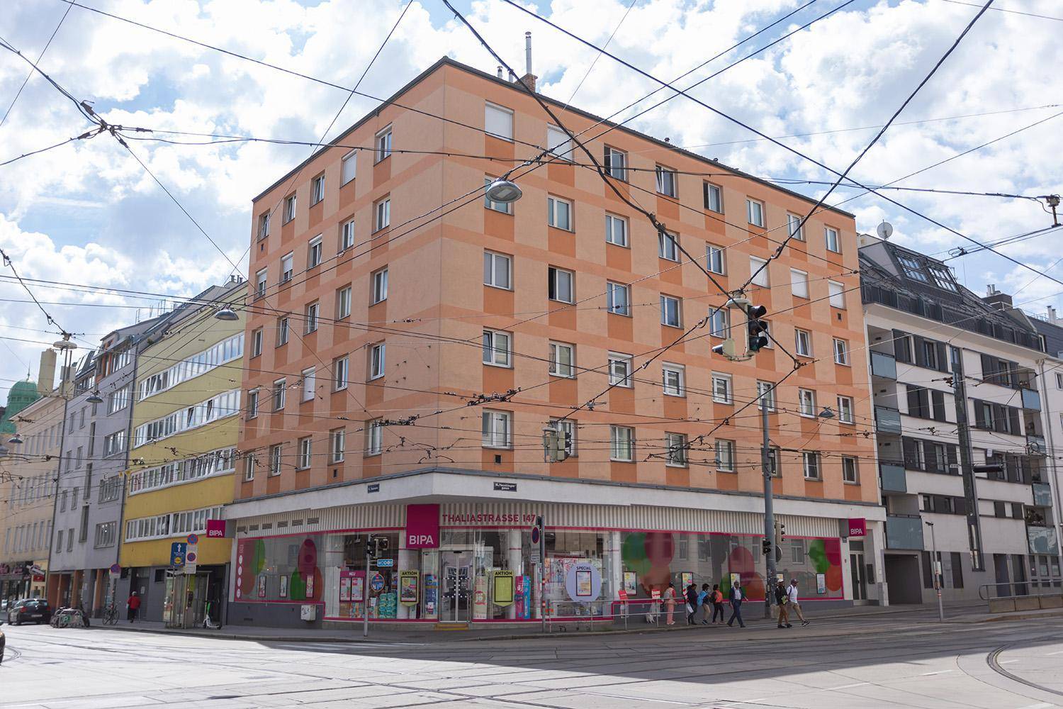 Mehrstöckiges Wohngebäude mit Geschäften im Erdgeschoss an einer belebten Straßenecke.