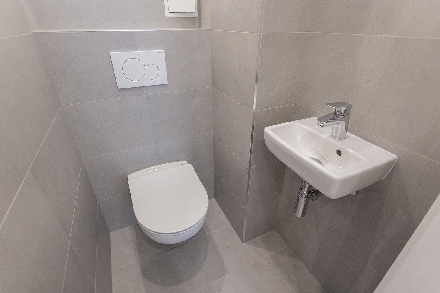 Detailansicht des Gäste-WCs mit wandhängender Toilette und kompaktem Waschbecken.