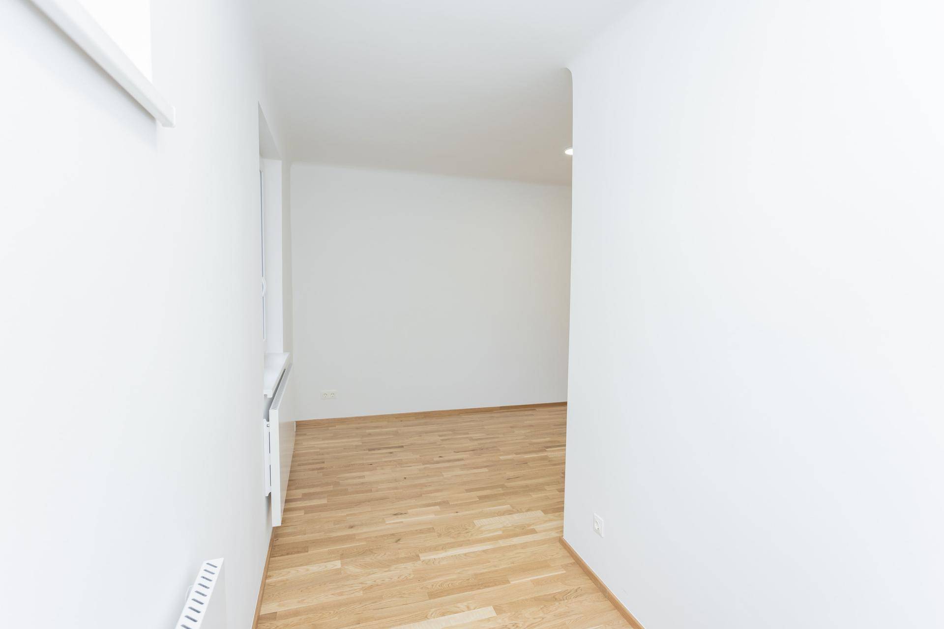 Heller Flur mit Holzboden und weiß gestrichenen Wänden, verbindet verschiedene Räume.