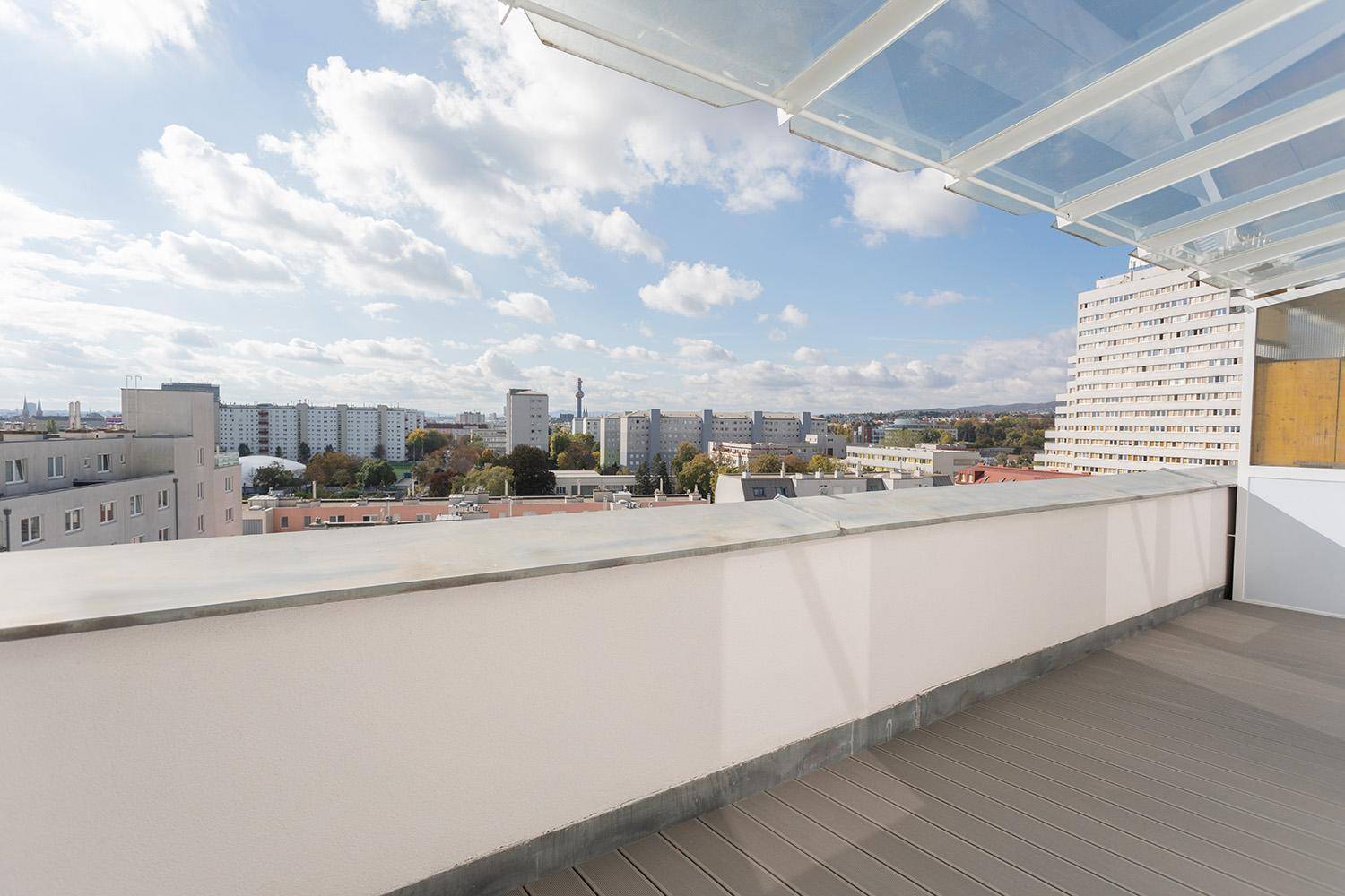 Geräumige Loggia mit Holzboden und Glasüberdachung bietet einen weiten Stadtblick.