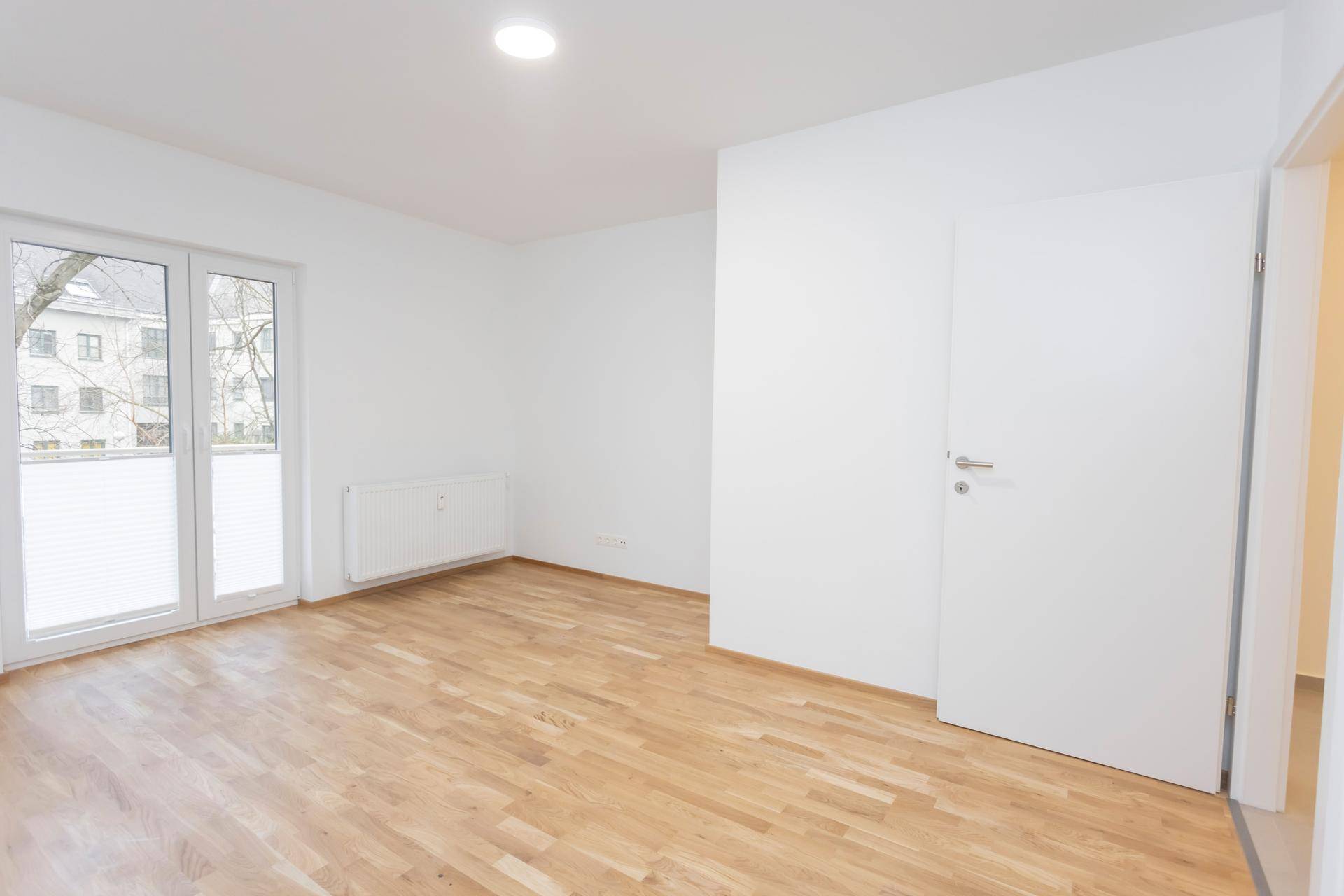Geräumiges Schlafzimmer mit Parkettboden und Zugang zu einem französischen Balkon.