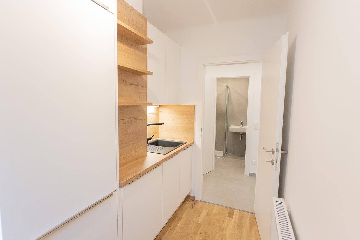 Küchenzeile mit Blick auf den Eingang zum Badezimmer, ausgestattet mit modernen Elementen.