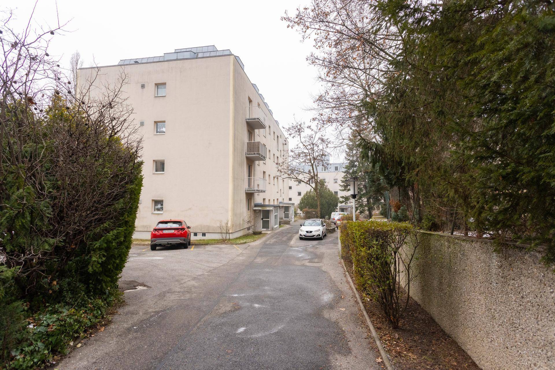 Ansicht eines Wohngebäudes mit Zufahrt und umliegender Vegetation.